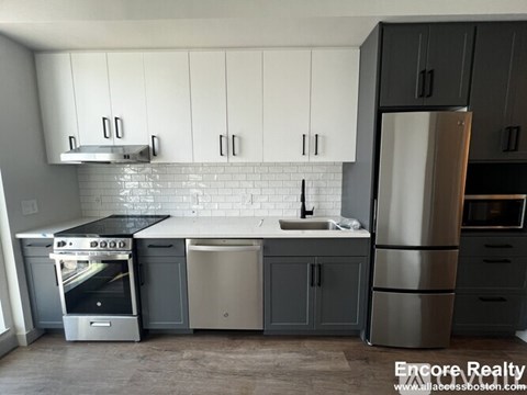 A kitchen with white cabinets and a stainless steel refrigerator.