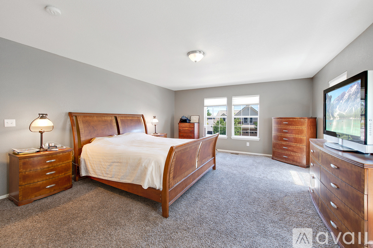 A bedroom with a large bed, dressers, and a flat-screen TV.