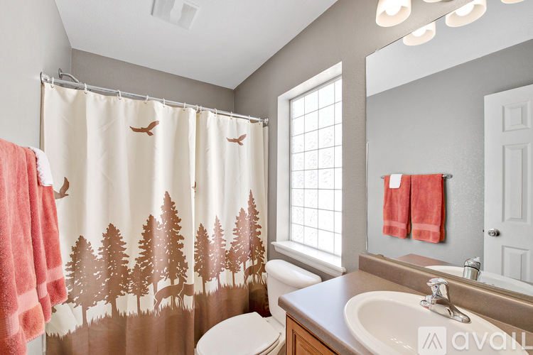 A bathroom with a shower curtain that has trees on it.