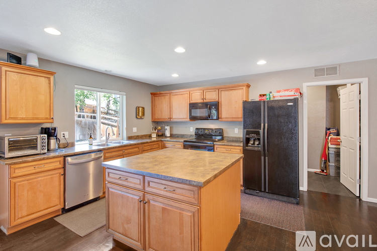 A kitchen with wooden cabinets and a black refrigerator.