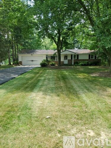 A house with a driveway and trees in front.