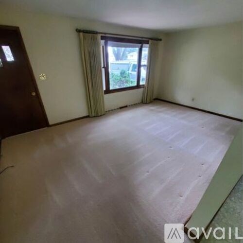 A room with a window and a door is available for rent.