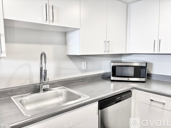 A modern kitchen with a stainless steel sink and microwave.