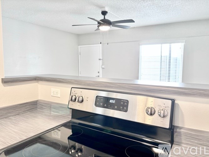 A modern kitchen with a stove top oven and a fan ceiling.
