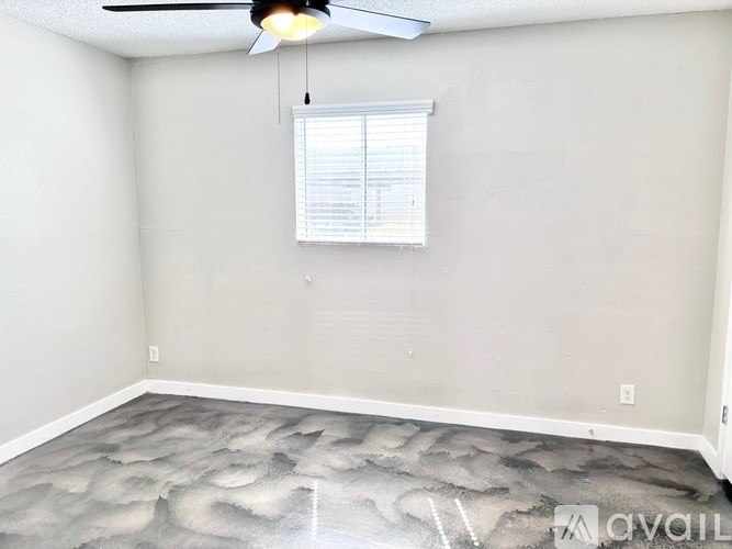 A room with a ceiling fan and a window with blinds.