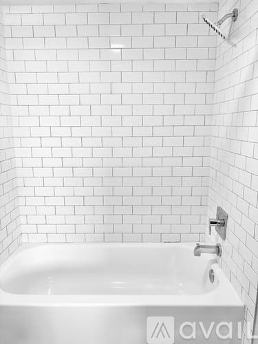 A white bathtub with a faucet and a white tiled wall.