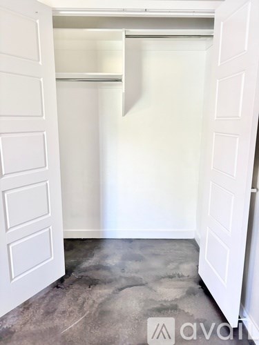A white door is open to a room with a grey floor.