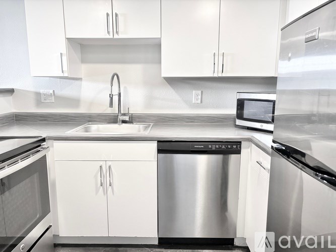 A modern kitchen with white cabinets and stainless steel appliances.
