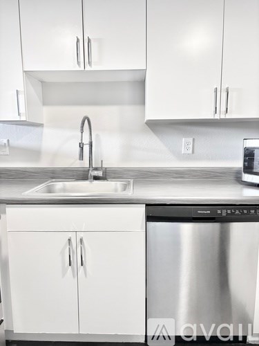 A kitchen with a stainless steel dishwasher and white cabinets.