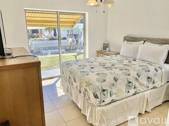 A bedroom with a bed, a television, and a sliding glass door.