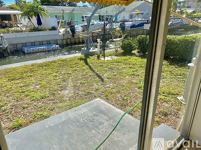 A view from a window looking out to a yard with a boat in the background.