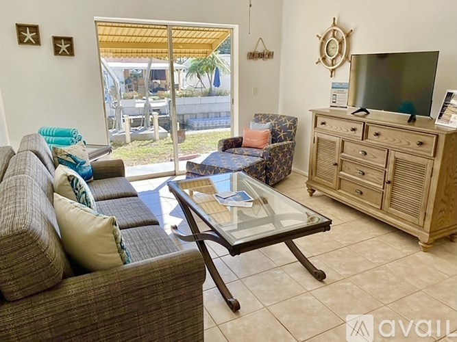 A living room with a couch, a glass table, and a television.