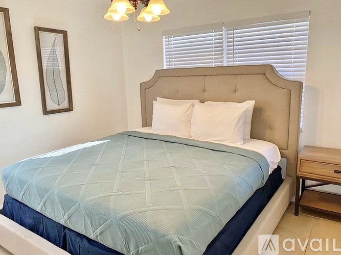 A bed with a blue comforter and a wooden nightstand.