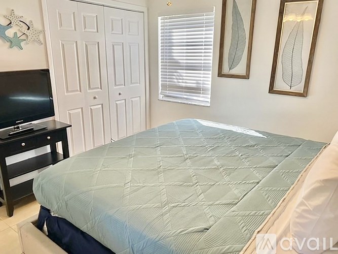 A bedroom with a bed, a dresser, and a television.