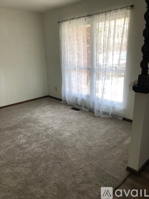 A room with a carpeted floor and a window with curtains.