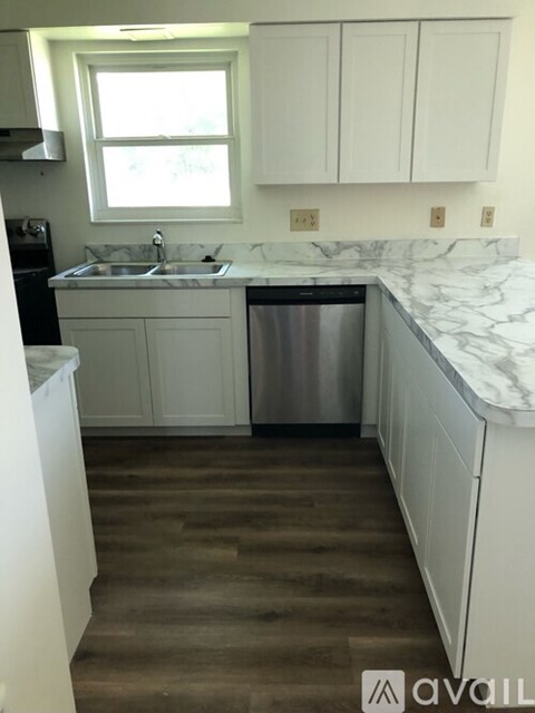 A kitchen with white cabinets and a marble countertop.