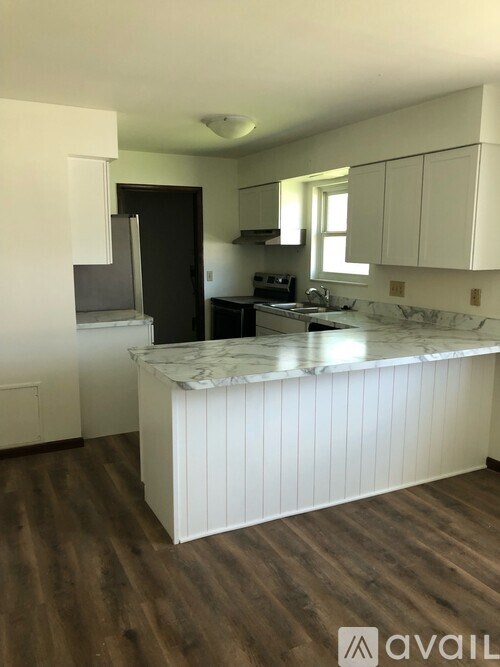 A kitchen with a marble countertop and wooden floors.