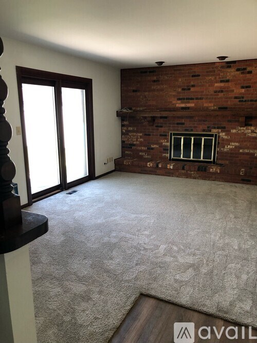 A room with a carpeted floor and a brick wall with a window.