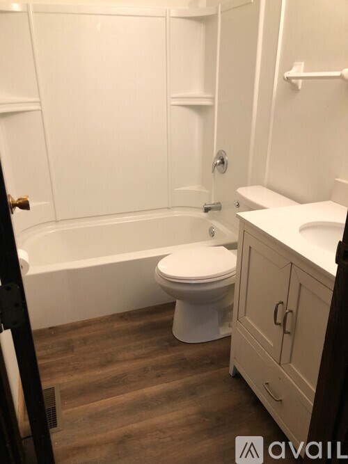 A white toilet sits in a bathroom next to a bathtub and a sink.