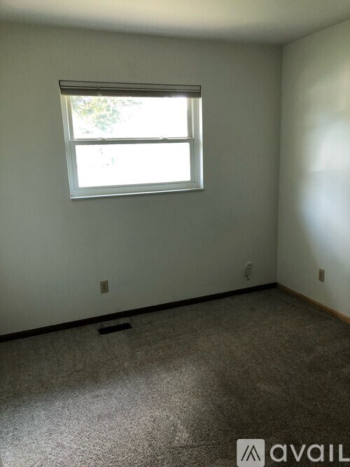 A room with a window and a carpeted floor.