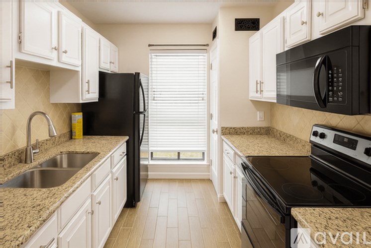 A kitchen with black appliances and white cabinets.