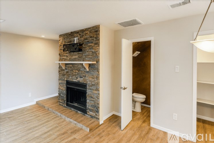 A room with a stone fireplace and a toilet in the corner.