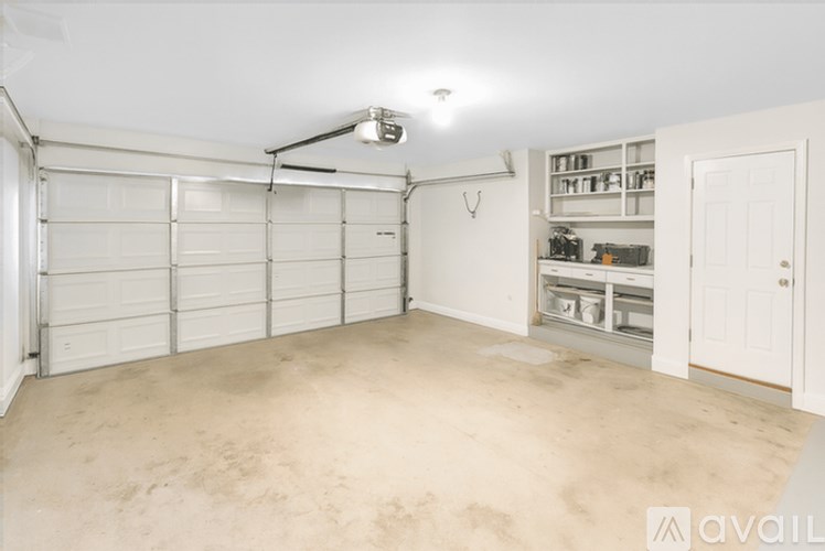A spacious garage with a white door and a white ceiling with a light fixture.