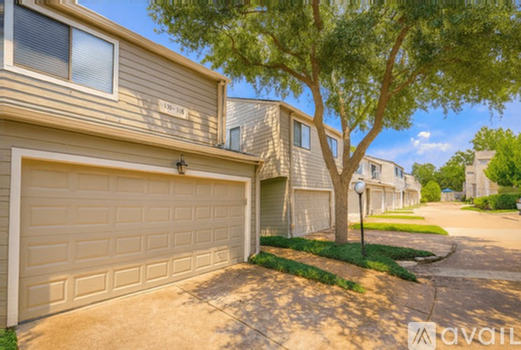 A tree is in front of a house with a garage door.
