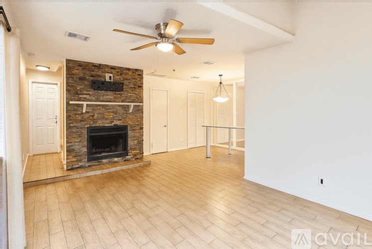 A living room with a fireplace and a ceiling fan.