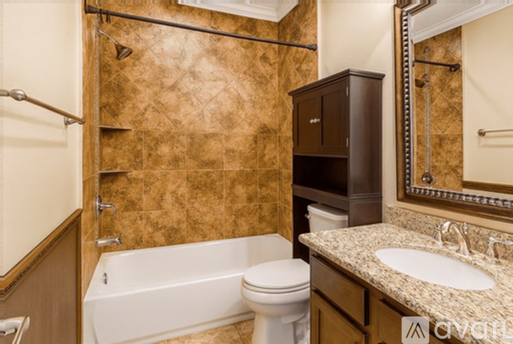 A bathroom with a brown tiled shower area and a white bathtub.