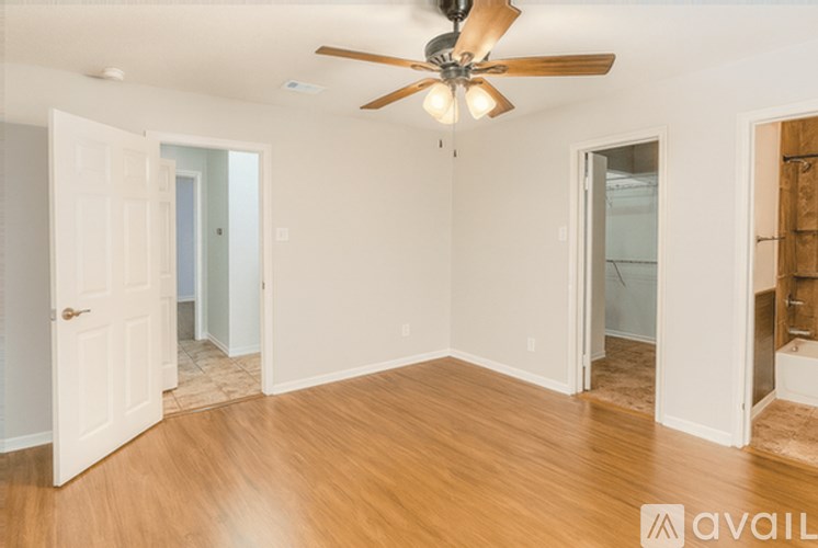 A room with a ceiling fan and wooden flooring.