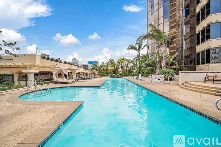 A large outdoor swimming pool surrounded by buildings and palm trees.