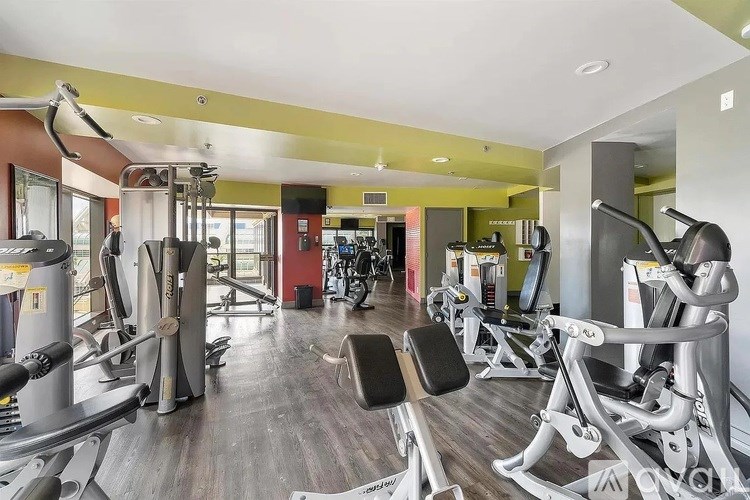 A gym with a variety of equipment including treadmills, weights, and exercise machines.