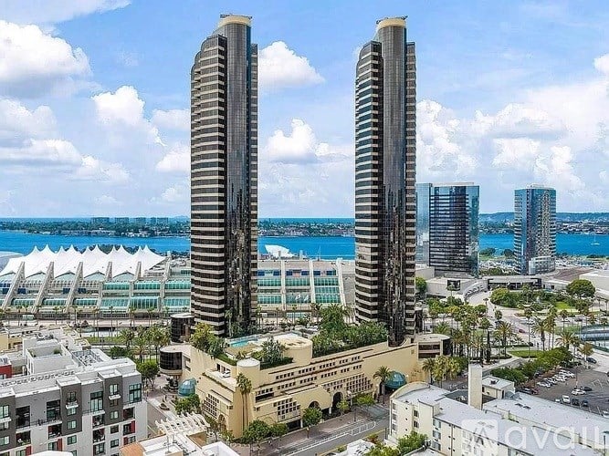 Two tall buildings stand in front of a body of water.
