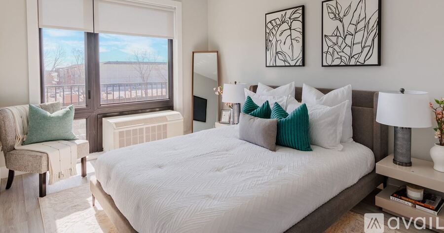 A bedroom with a large bed, a chair, and two framed artworks on the wall.