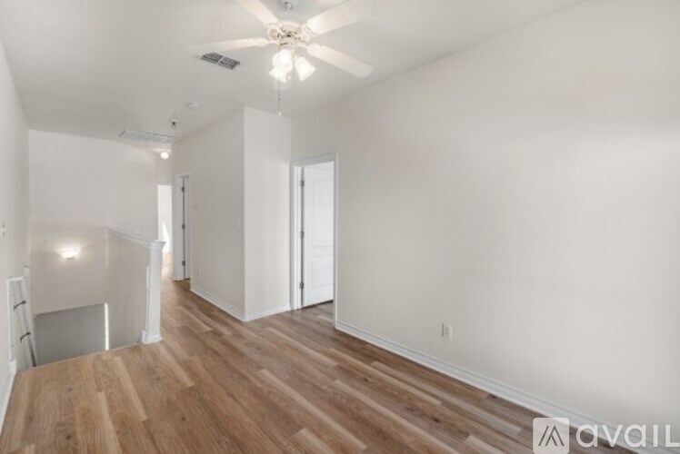 A spacious room with wooden floors and a ceiling fan.