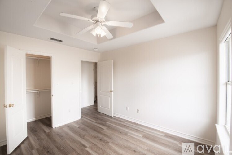 A room with a ceiling fan and wooden flooring.