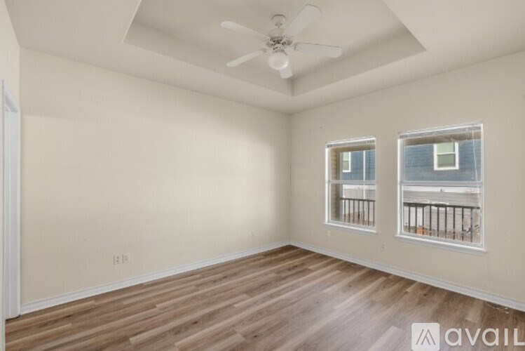 A room with a ceiling fan and two windows.