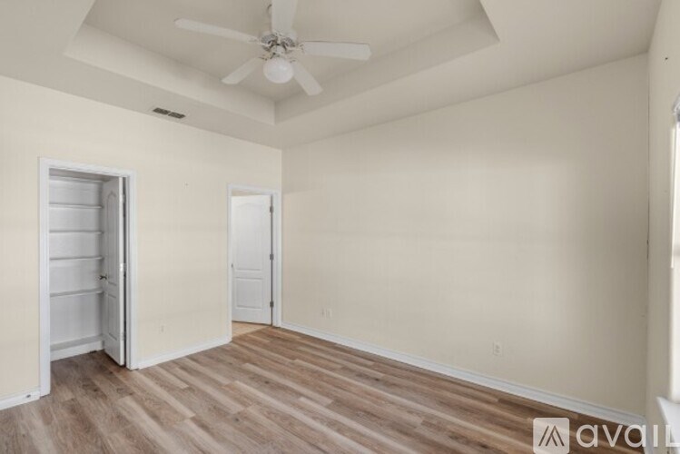 A room with a ceiling fan and wooden flooring.