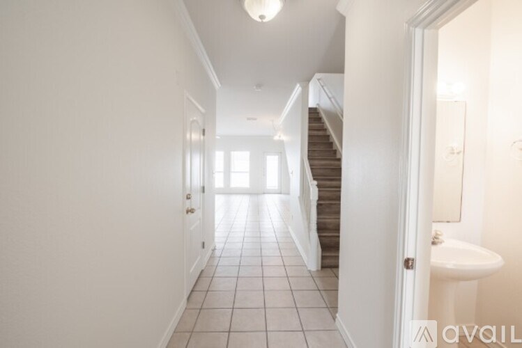 A hallway with a staircase and a toilet visible through the door.