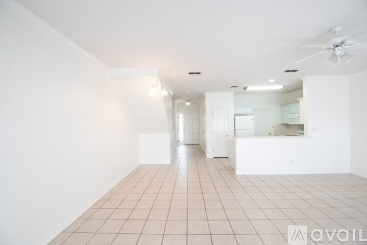 A spacious room with tiled flooring and a ceiling fan.