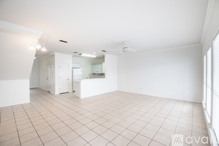 A spacious, empty room with white cabinets and a tiled floor.