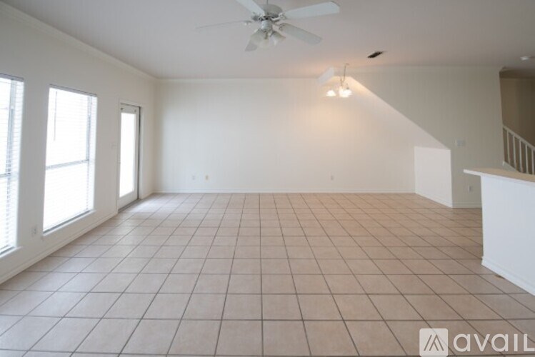 A spacious room with a ceiling fan and tiled flooring.