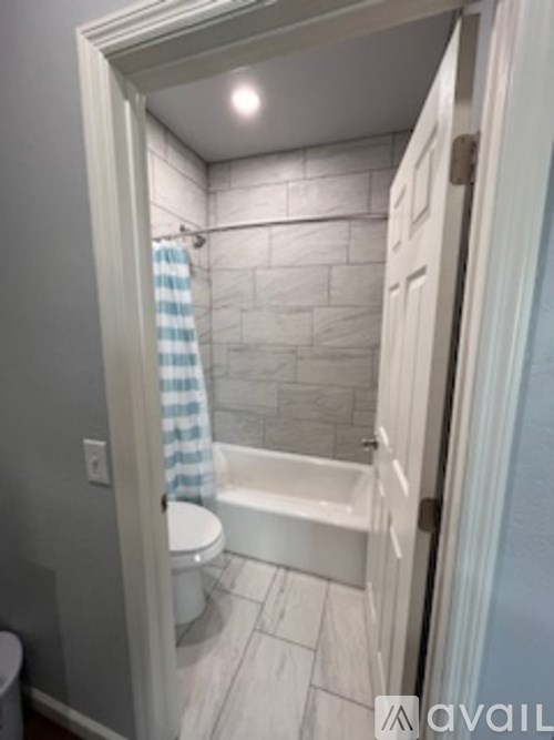 A bathroom with a toilet, a bathtub, and a shower curtain.
