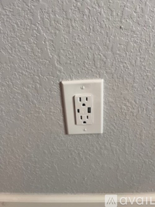 A white electrical outlet on a textured wall.