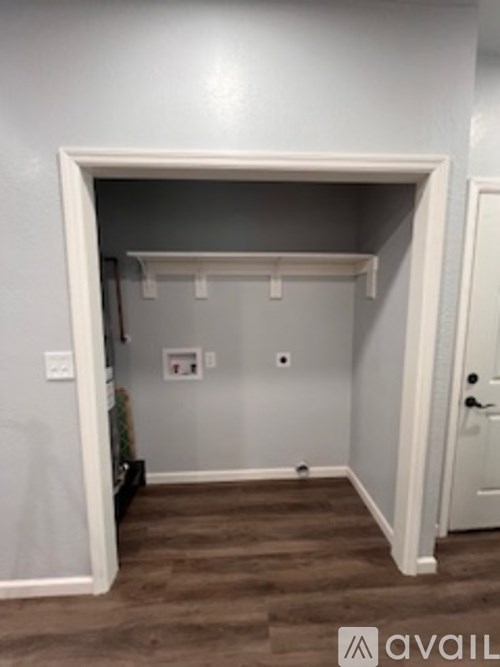 A white doorway leads to a room with a grey wall and a wooden floor.