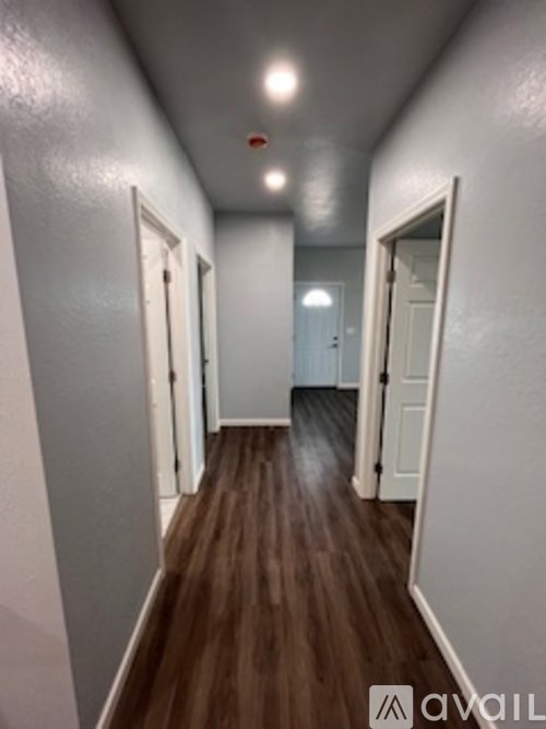 A long hallway with white walls and wood flooring.