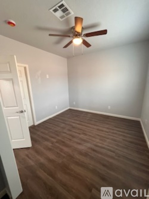 A room with a ceiling fan and wooden flooring.