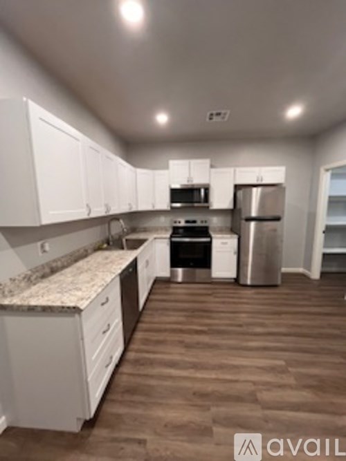 A kitchen with white cabinets and a granite counter top.