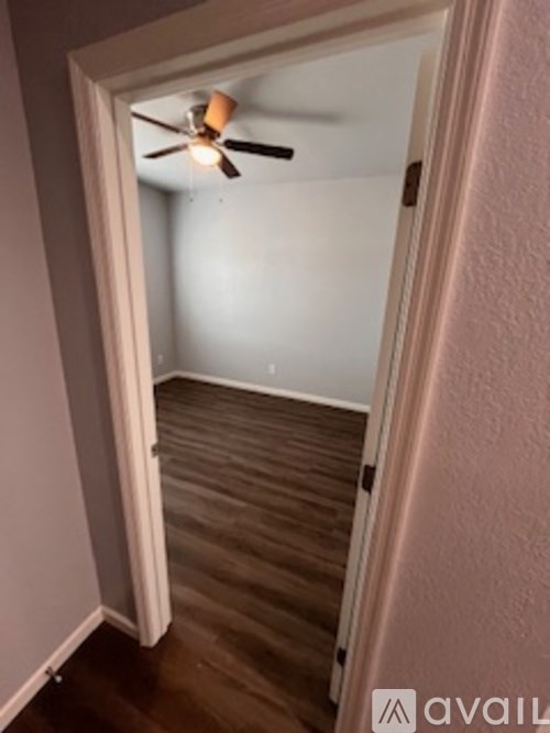 A room with a ceiling fan and wooden flooring.